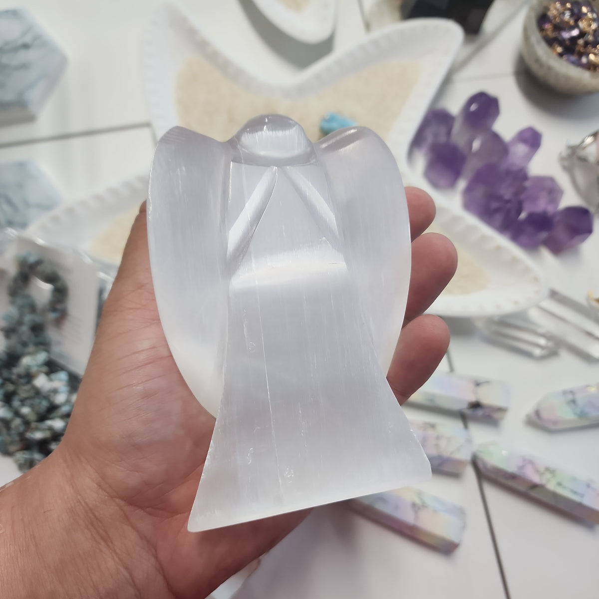 Hand holding a white angel carving with folded wings.
