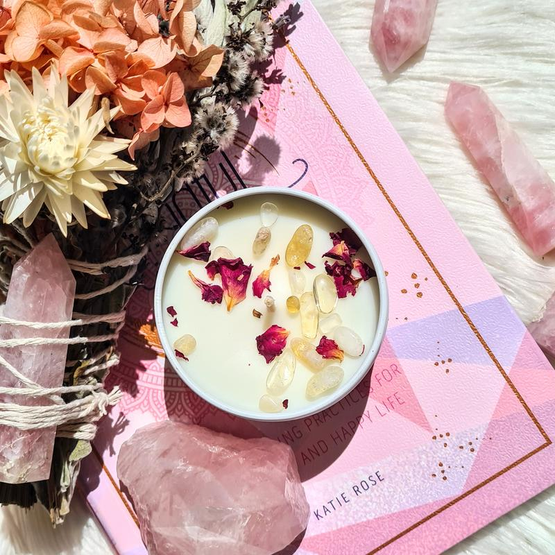 Botanical-topped candle beside flowers, pink crystals and a pink book.