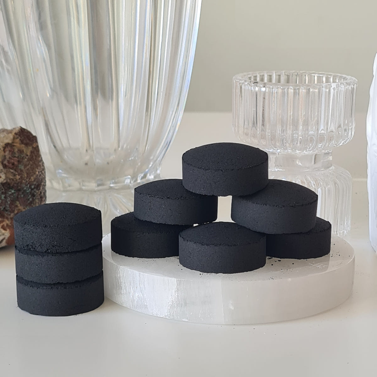Round black charcoal tablets stacked on a white circular display base.