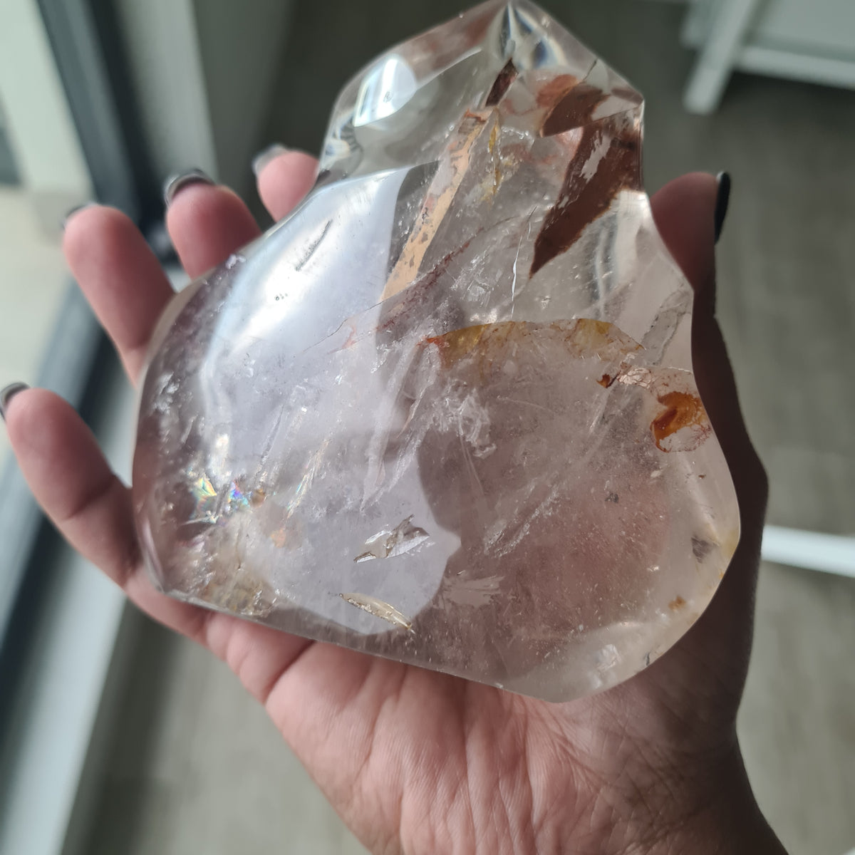 Hand holding a polished quartz flame with smoky tones and natural inclusions.