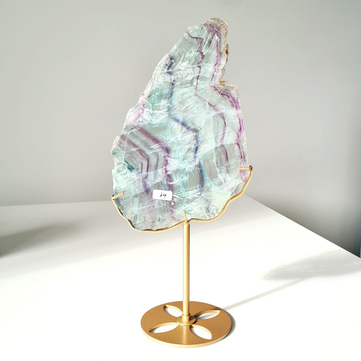 Irregular fluorite Dream Portal slab with pale green and purple bands mounted on a gold-coloured stand.