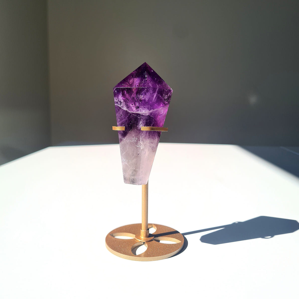 Amethyst crystal wand with a deep purple tip and pale lower section on a gold-coloured stand.