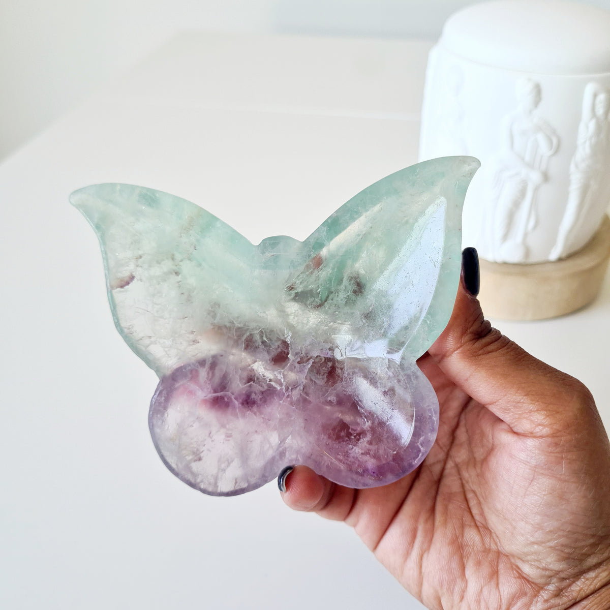 Hand holding fluorite butterfly bowl 02 with pale green upper wings and lilac lower wings.