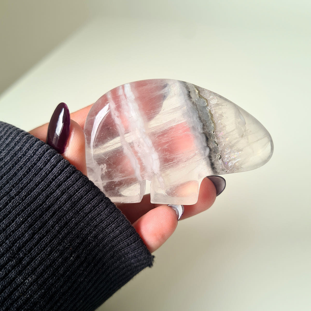 Hand holding a translucent Quartz bear carving with pale white bands.