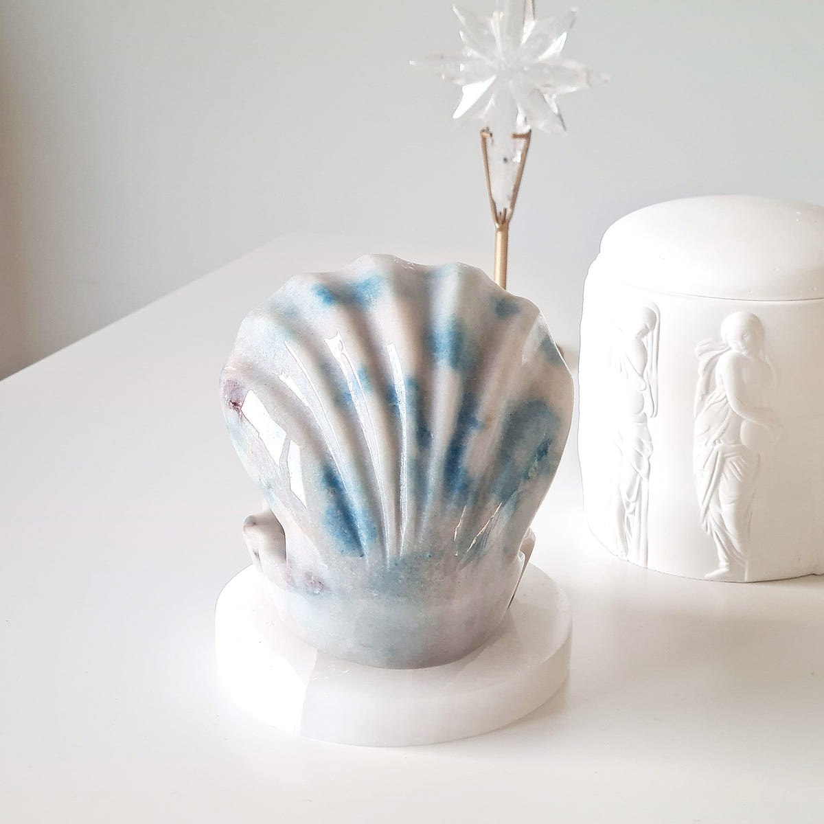 Trolleite shell carving with narrow ridges and blue stripes over a pale base.