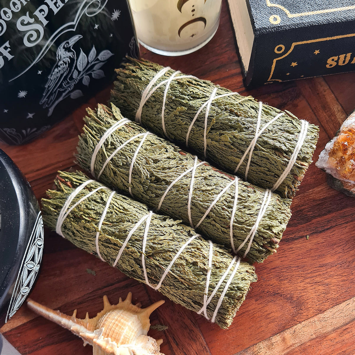 Three dark-green Cedar smudge bundles tied with white string.