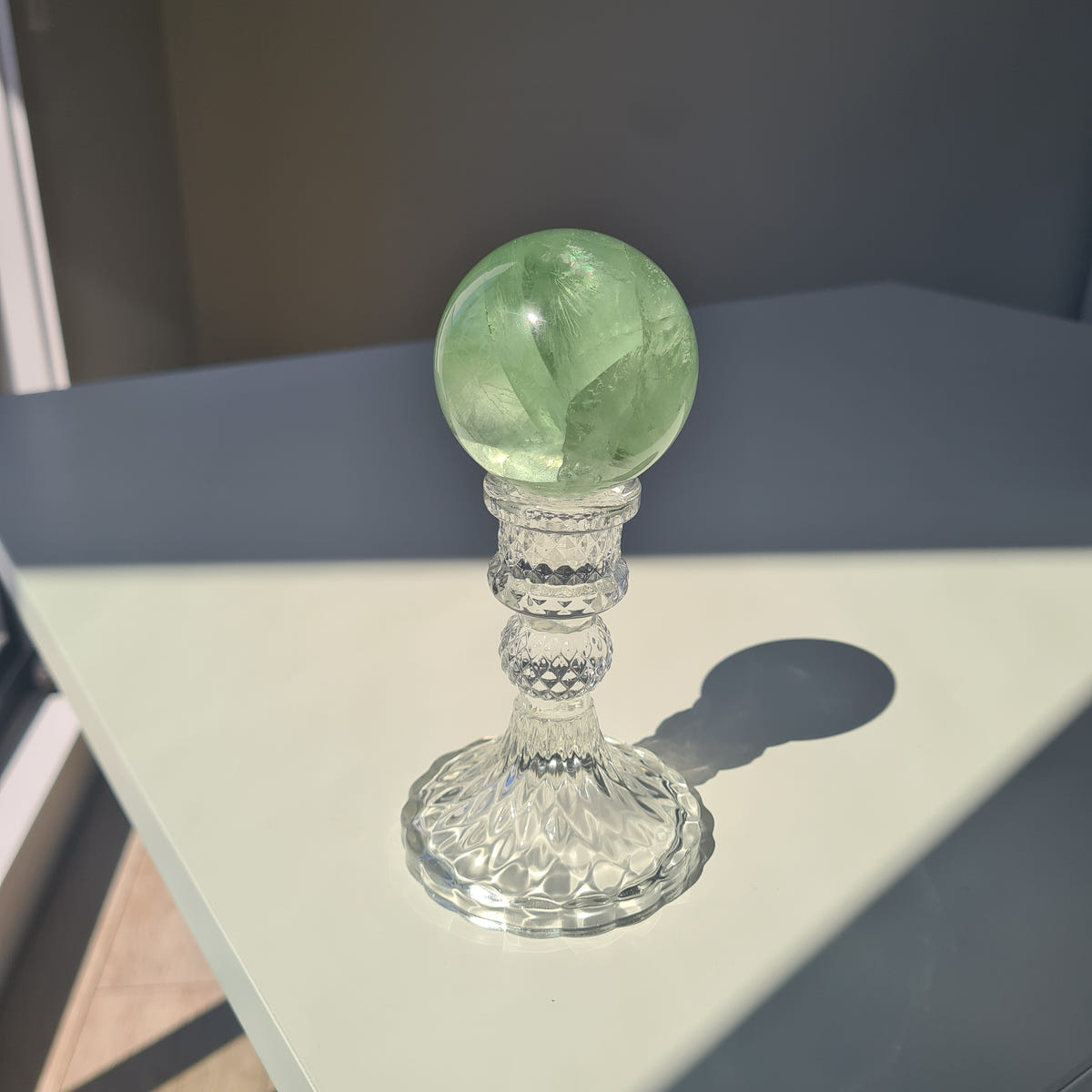 Green Frozen Lake fluorite sphere E with translucent cloudy sections on a clear decorative stand.