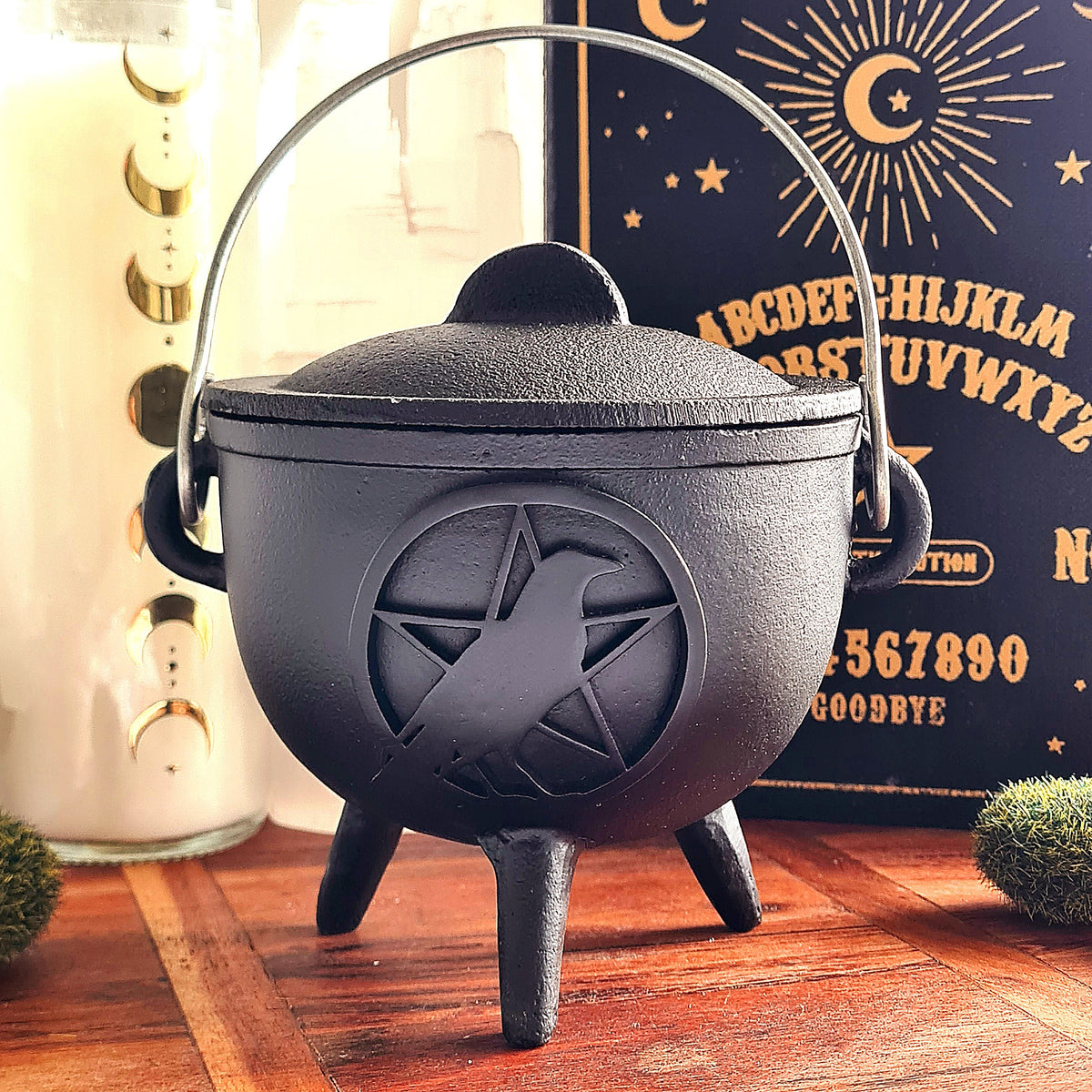 Black cast iron Raven ritual cauldron with raven centred inside a pentagram, shown with lid in place.