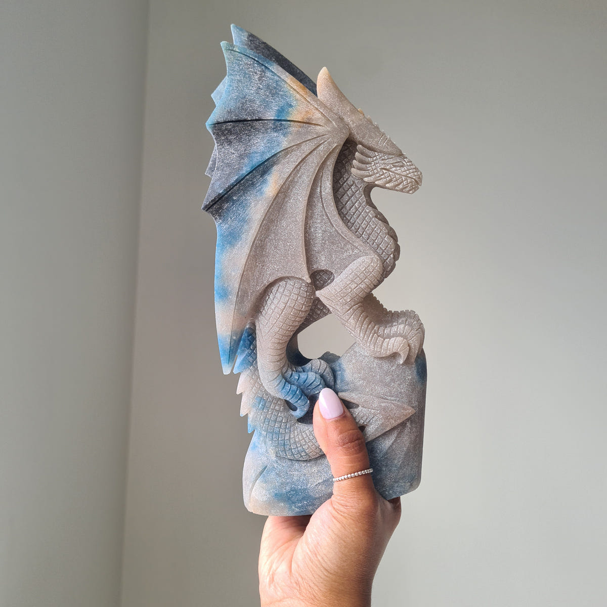Hand supporting a large pale and blue trolleite dragon carving.