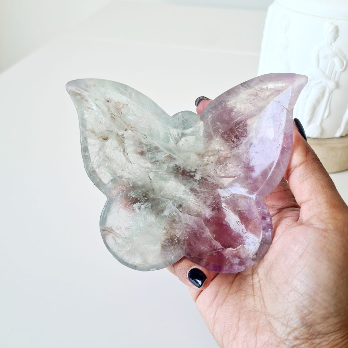 Hand holding fluorite butterfly bowl 04 with cloudy mint and purple wings.