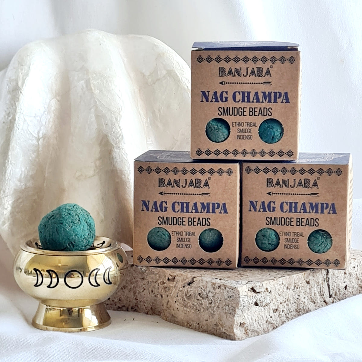 Three Banjara Nag Champa smudge bead boxes beside a brass burner holding a teal round bead.