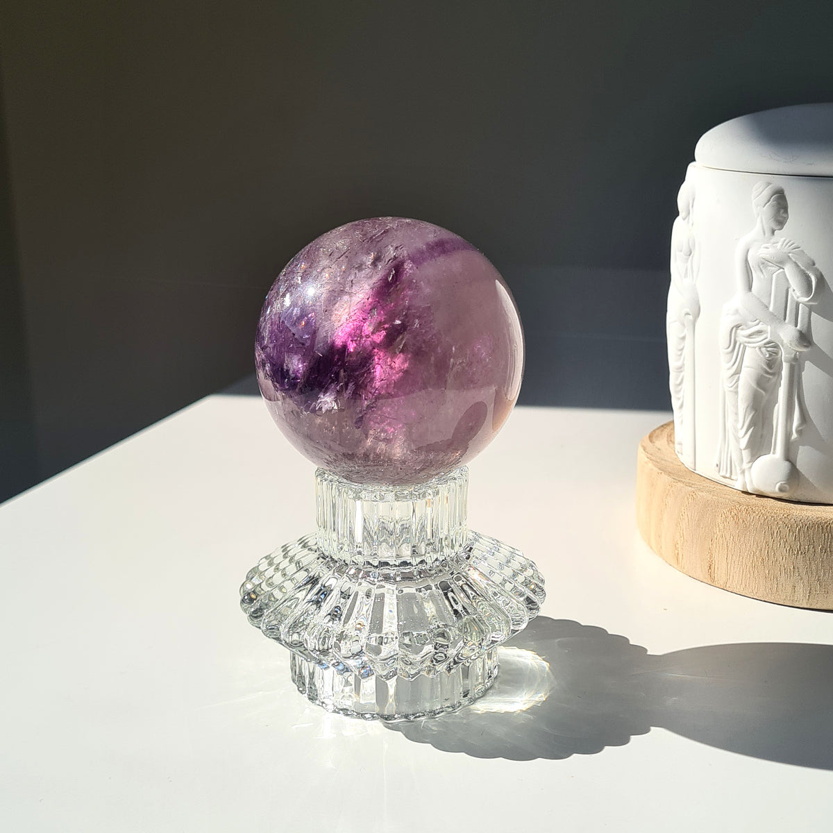 Amethyst phantom sphere with purple bands and pale inclusions on a clear decorative stand.