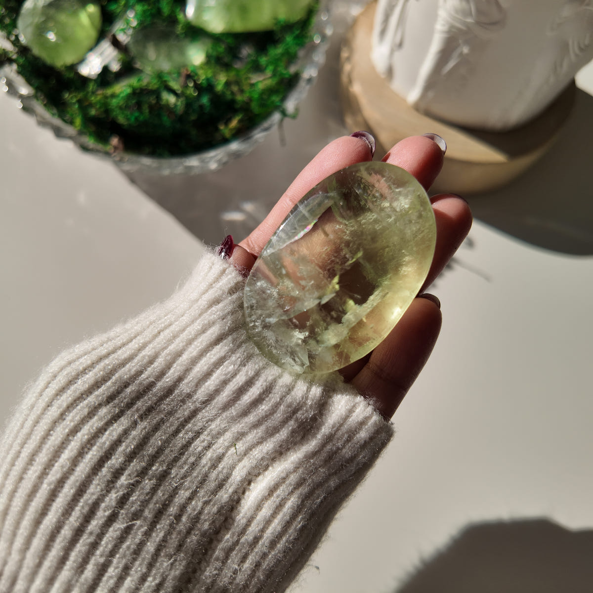 Hand holding polished pale-green Fluorite pocket stone P, with translucent areas and internal veils.
