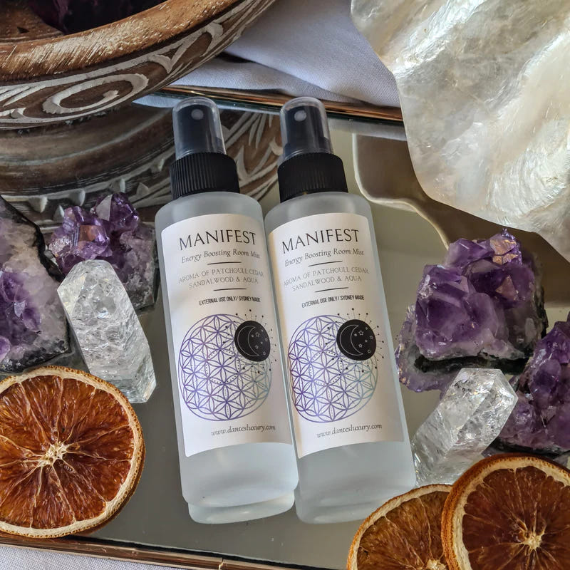 Two ritual mist spray bottles displayed among crystals and dried orange slices.