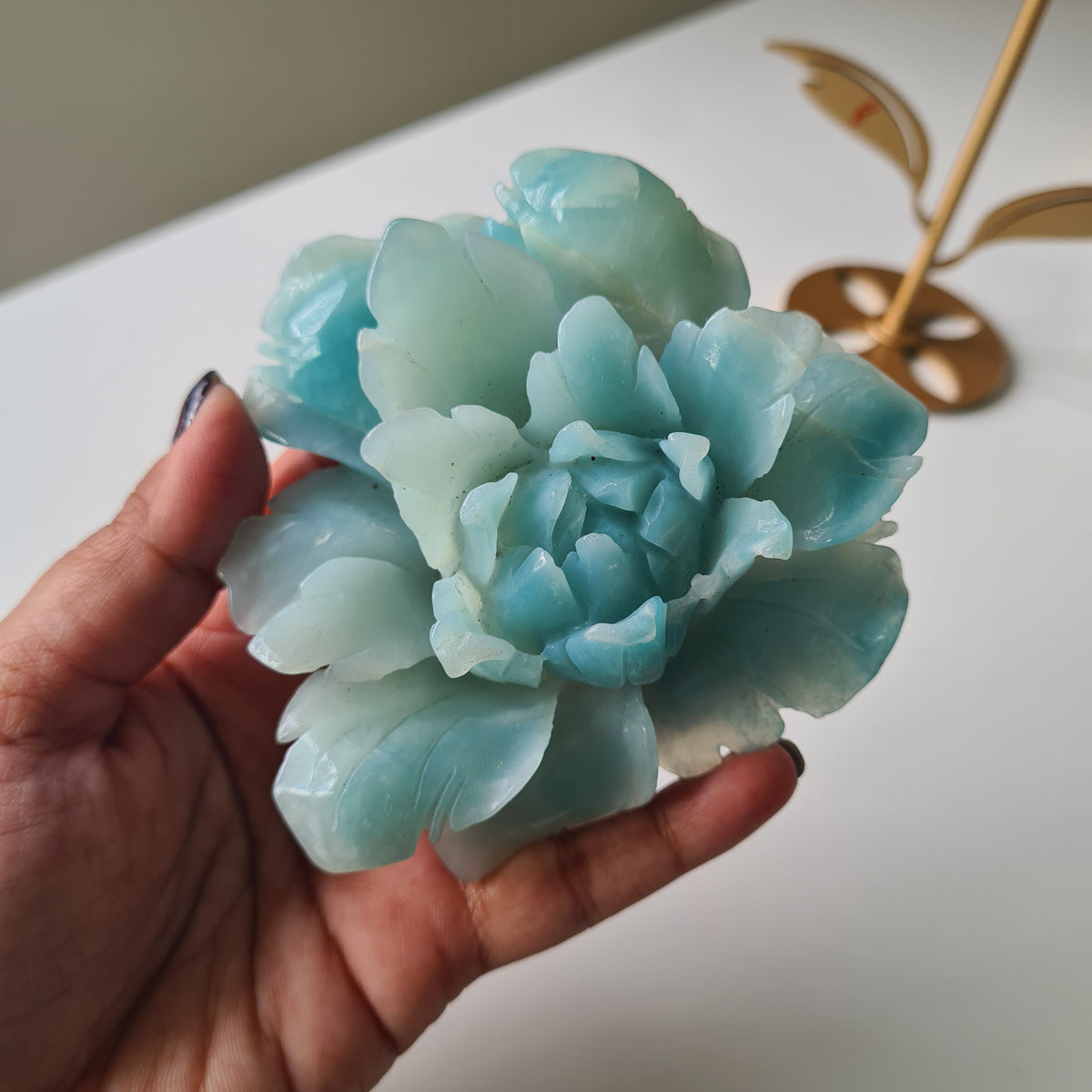 Caribbean Calcite Crystal Flower On Stand, 9 cm, held in a hand to show its aqua carved petals.