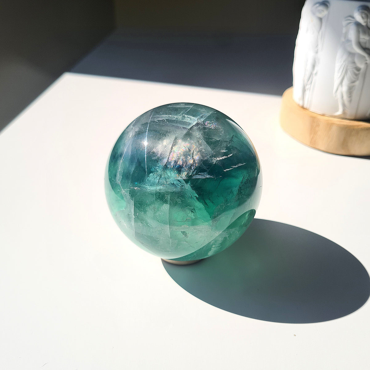 Green Fluorite sphere, 8.4 cm, with translucent teal tones and natural internal formations, displayed in sunlight.