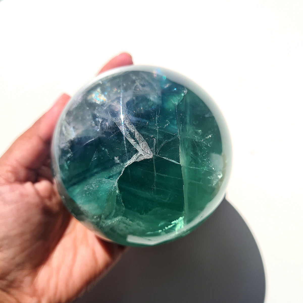 Green Fluorite sphere, 8.4 cm, with translucent teal tones and natural internal formations, held in a hand.