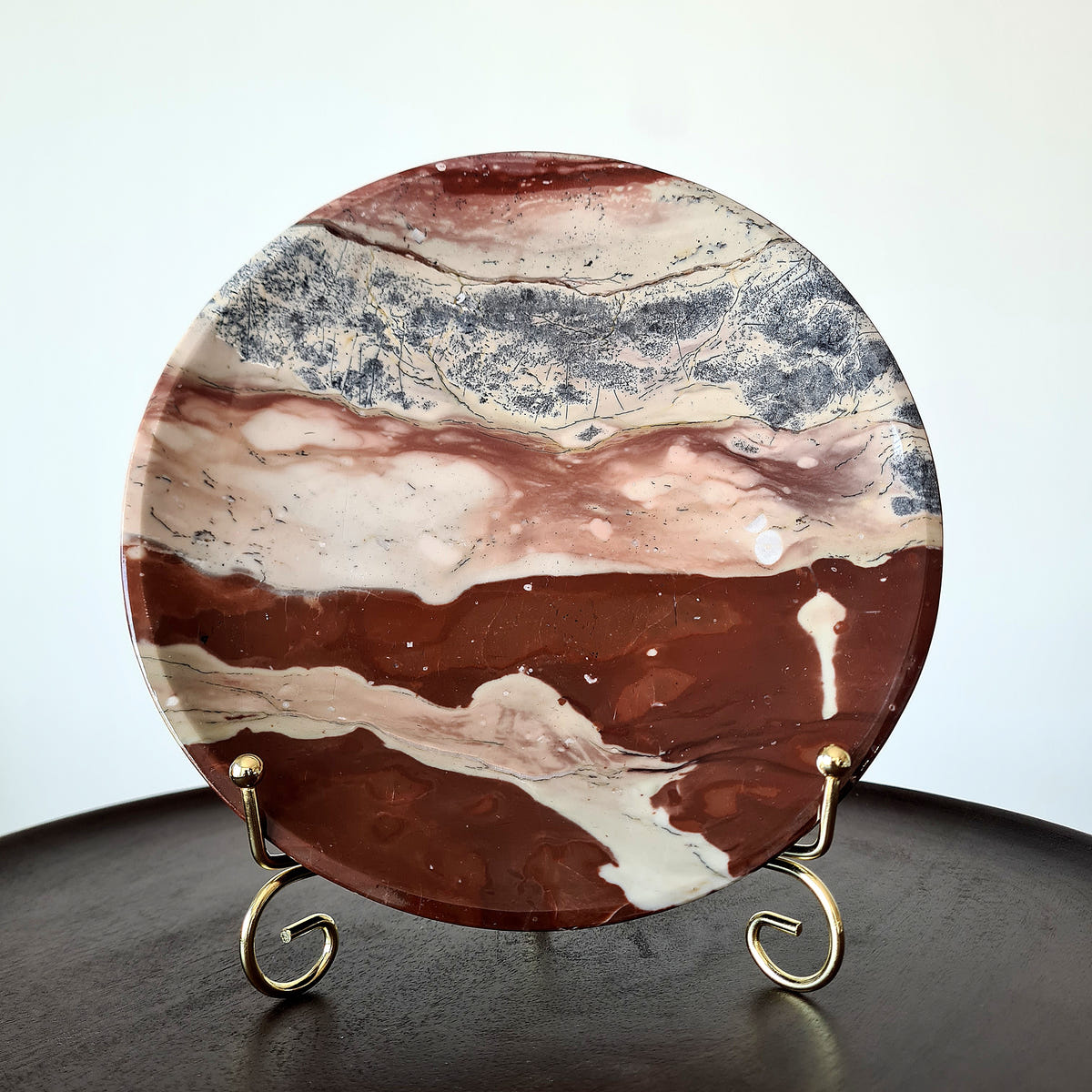 Round picture jasper plate with broad cream, red-brown and grey bands, displayed upright on a metal stand.