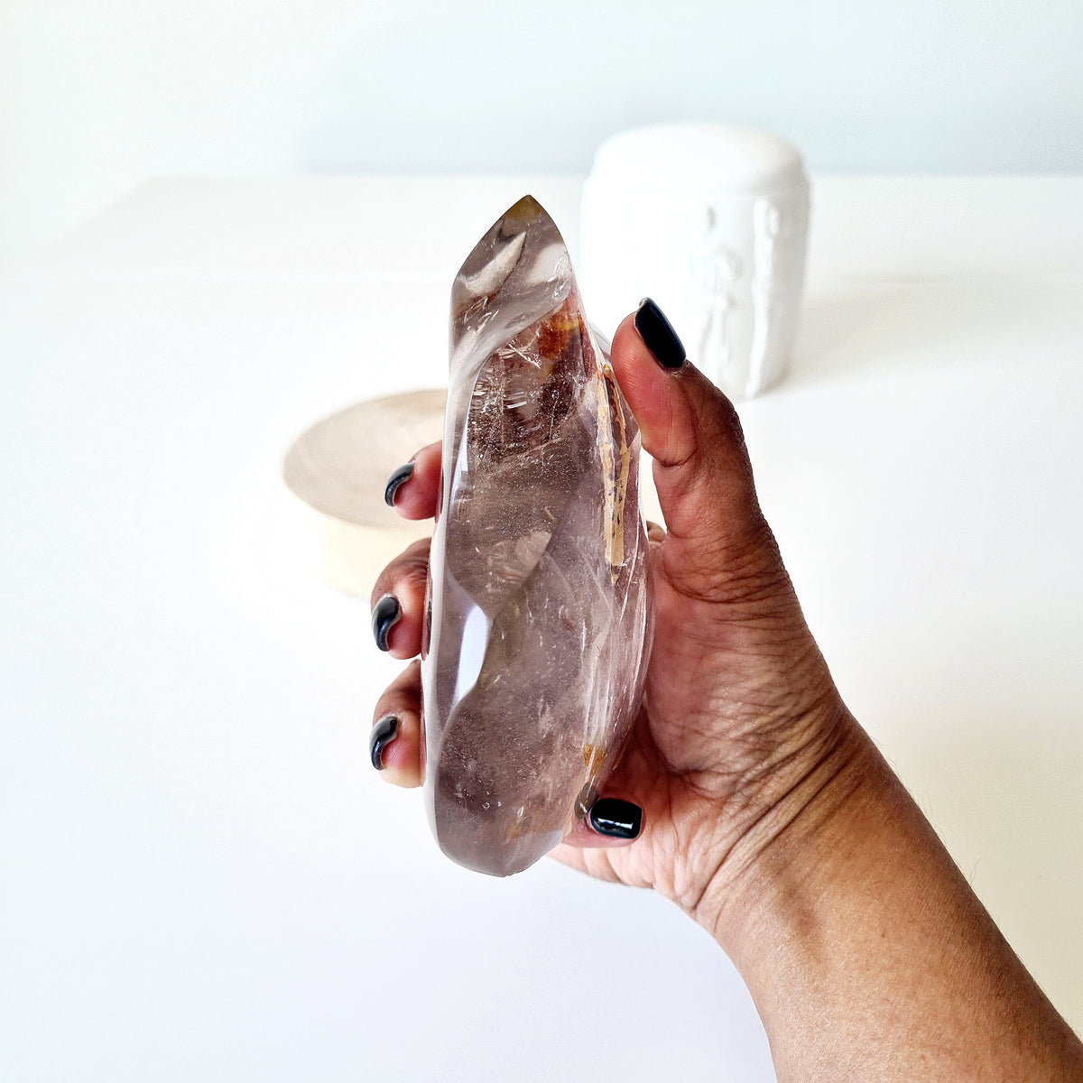 Narrow side view of a polished quartz flame held in a hand.