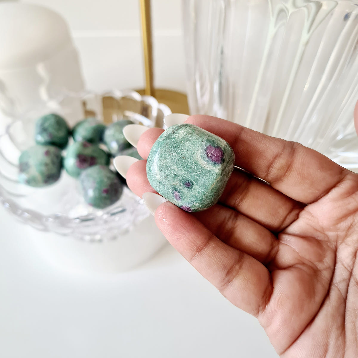 Hand holding ruby in fuchsite tumble 01 with a round pink spot and a pale green band.