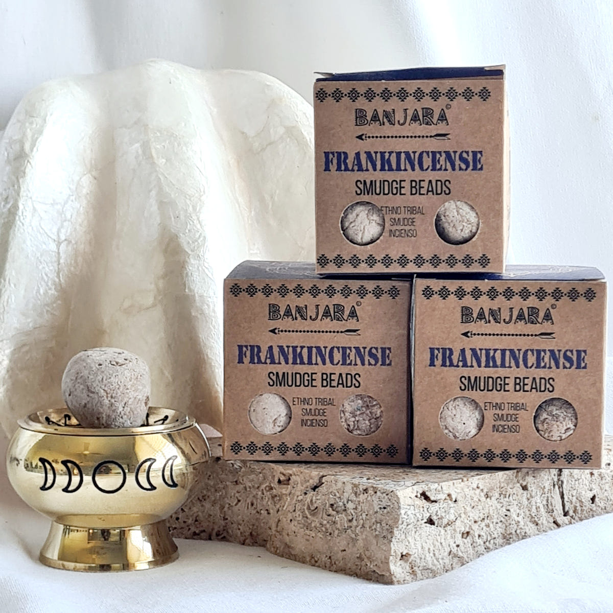 Three Banjara Frankincense smudge bead boxes beside a brass moon-design burner holding a pale round bead.