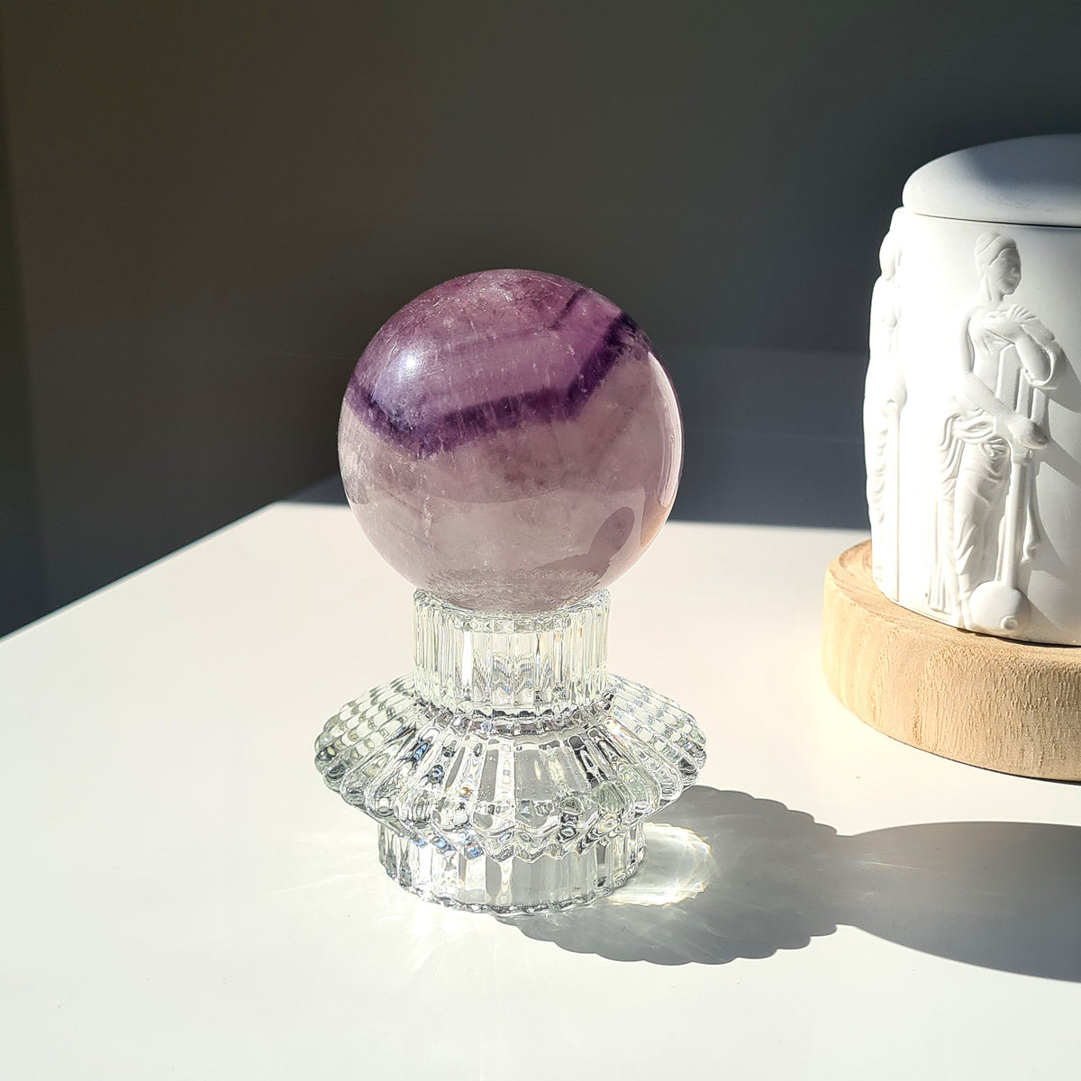 Amethyst phantom sphere with purple bands and pale inclusions on a clear decorative stand.
