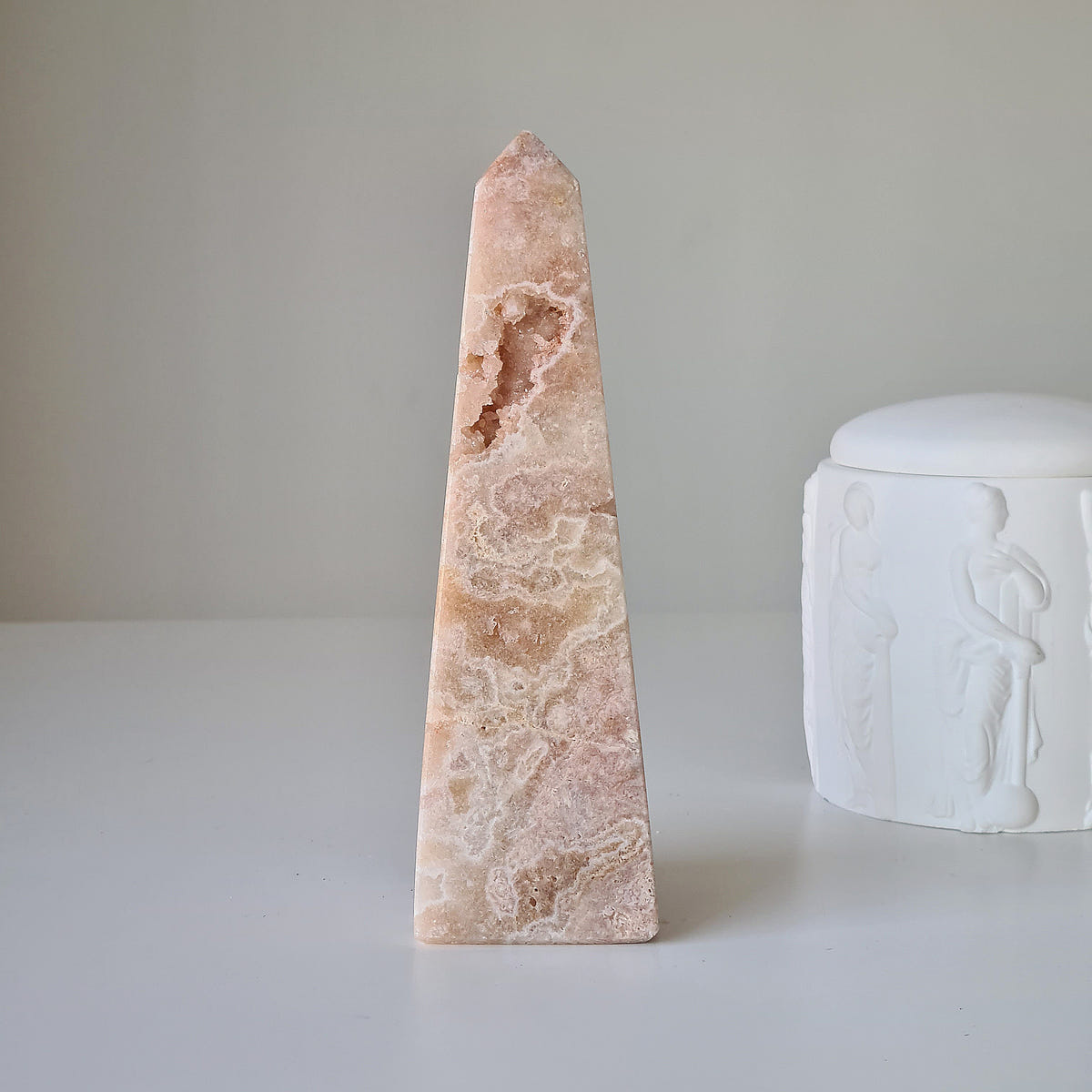 Tall pink amethyst obelisk with pale wavy bands and a natural crystal pocket near its pointed top.