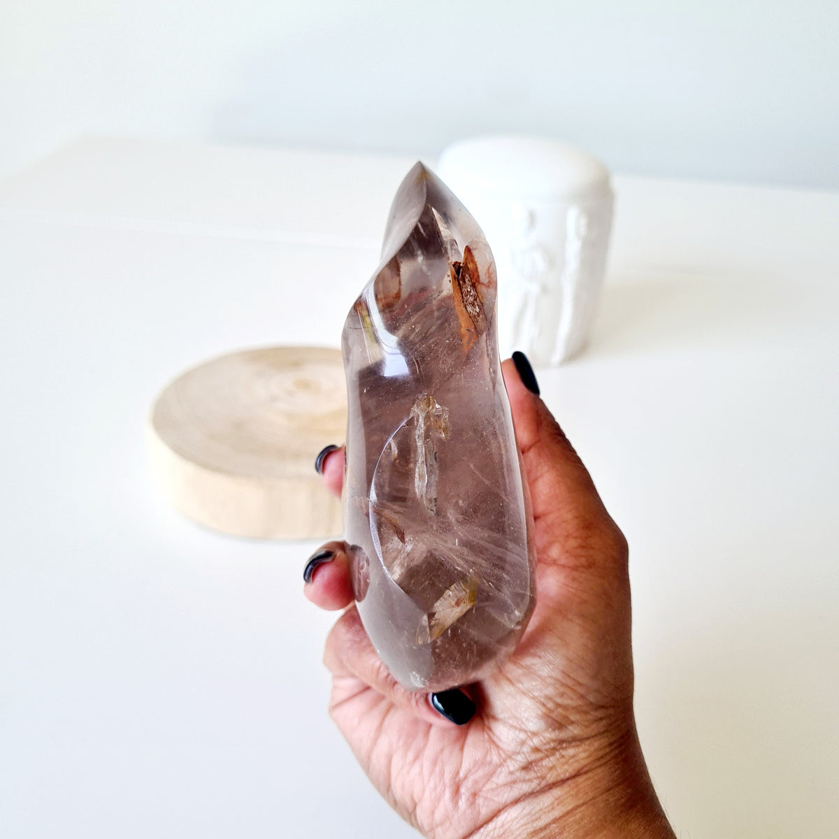 Narrow side view of a polished quartz flame held in a hand.