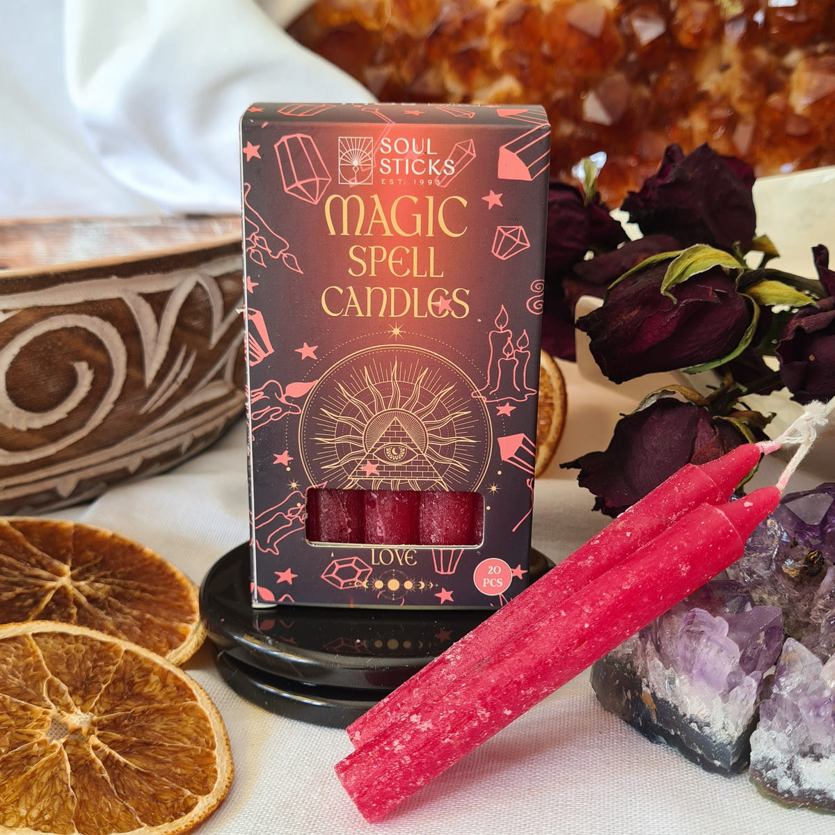 Love Magic Spell Candles box beside two red candles, dried orange slices and rose petals.