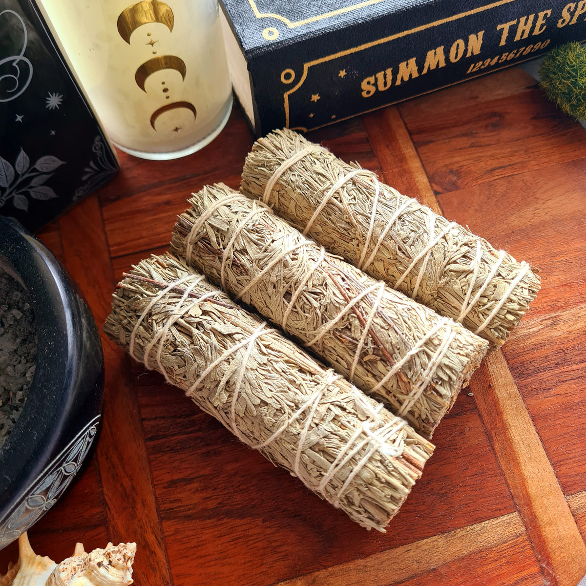 Pale-grey Blue Sage smudge bundles tied with white string on wood.