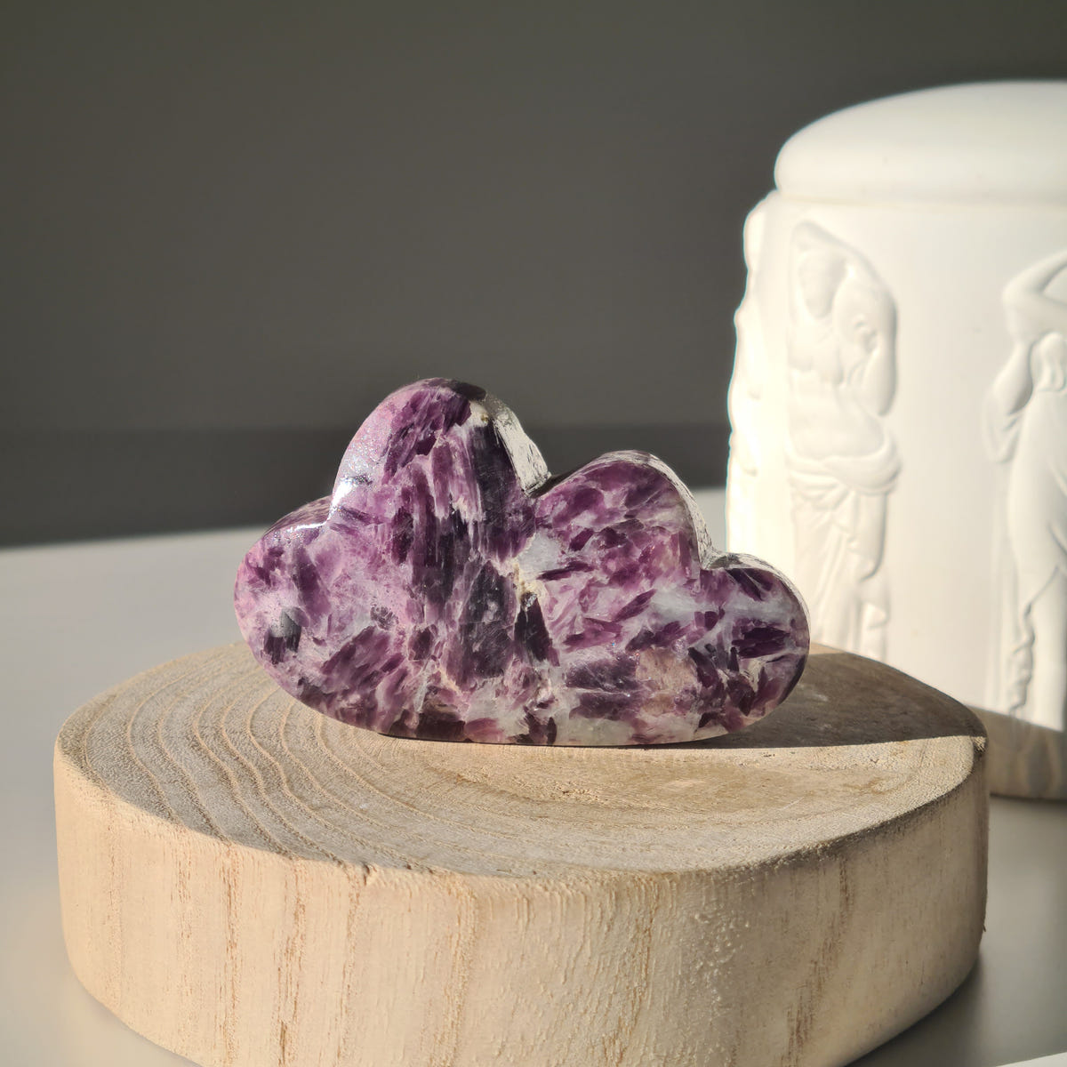 Lepidolite cloud carving A with tall rounded lobes and streaked purple and white patterns on a wooden base.