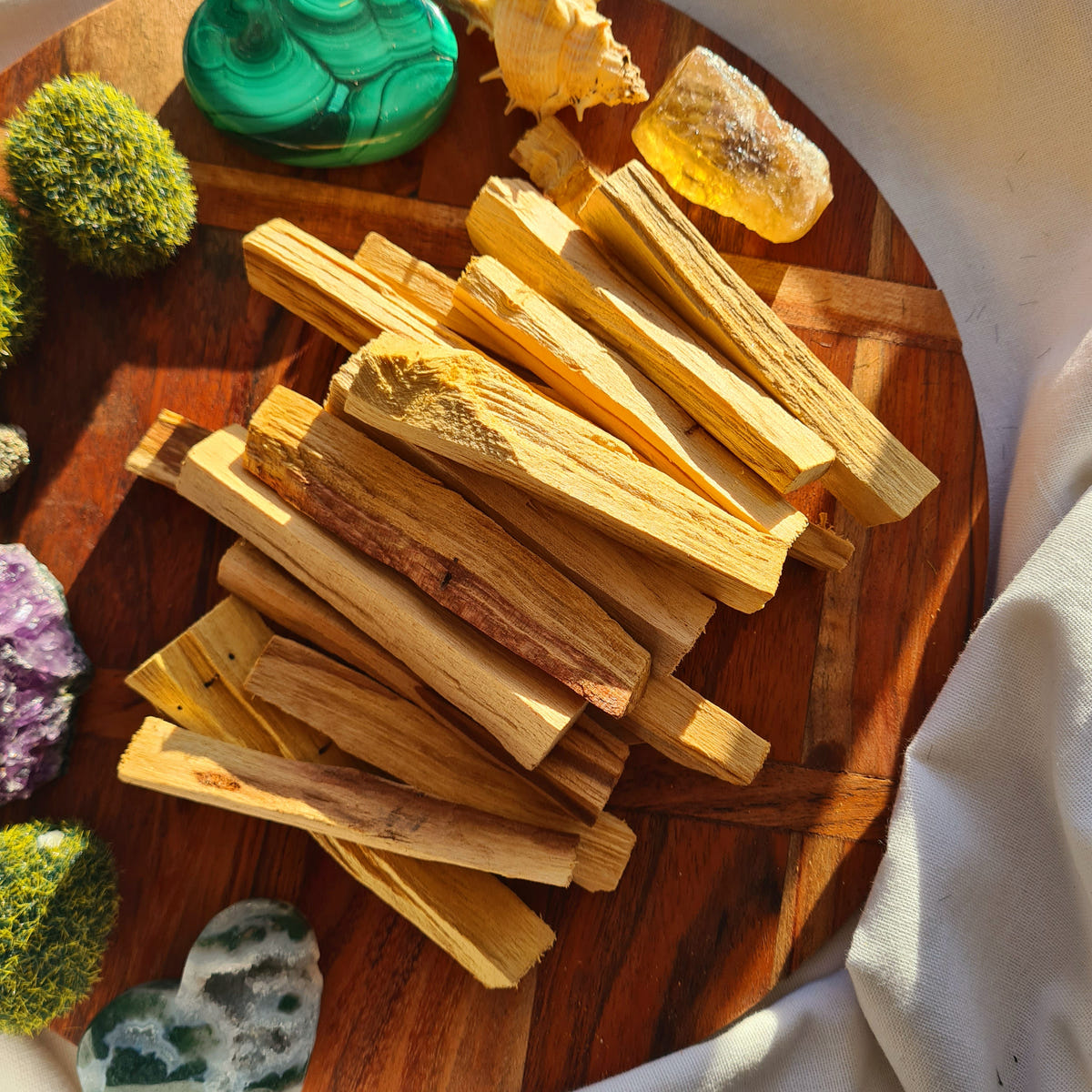Thin golden-brown Palo Santo wood sticks arranged in a shallow wooden bowl.
