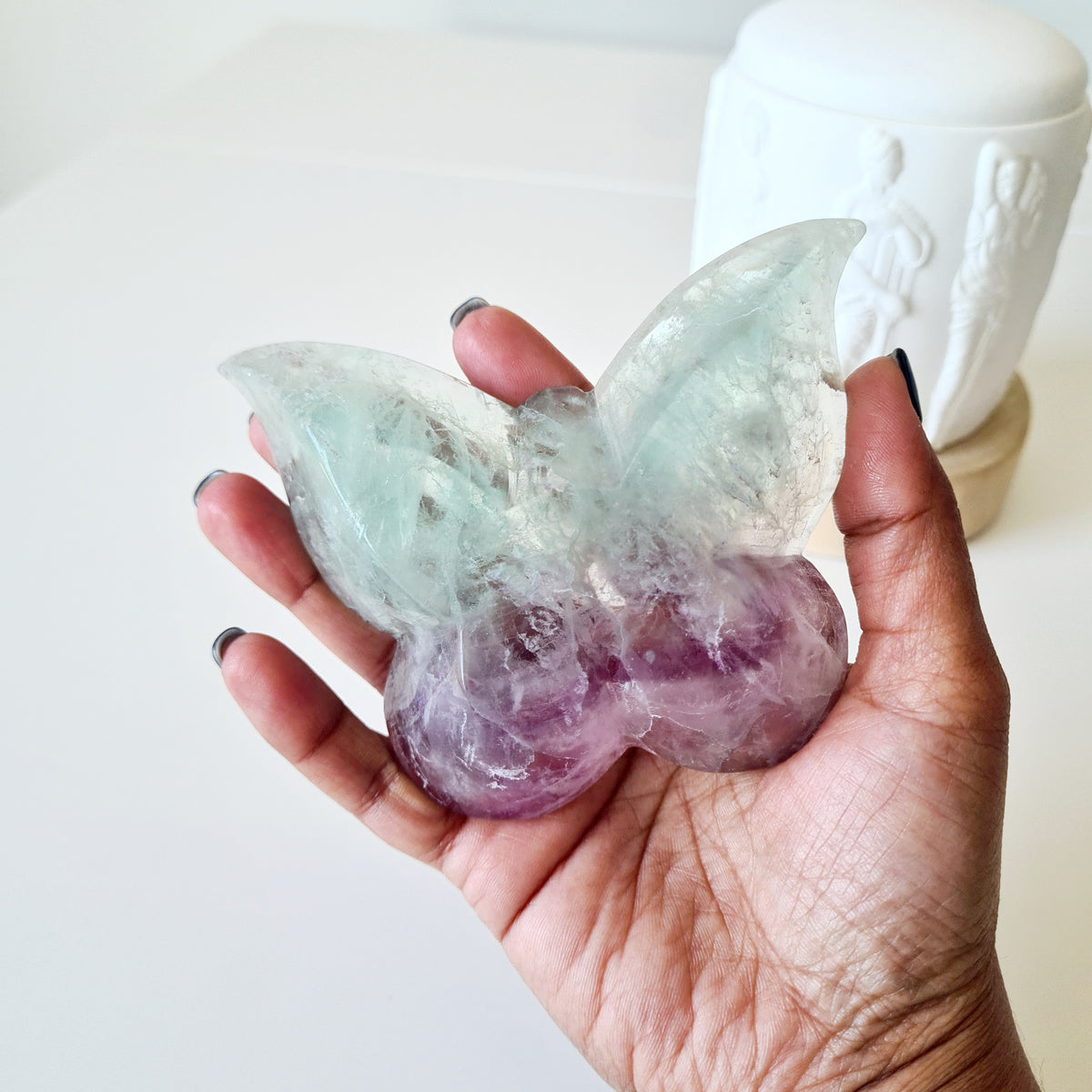 Fluorite butterfly bowl in a hand, showing pale green upper wings and lilac lower wings.