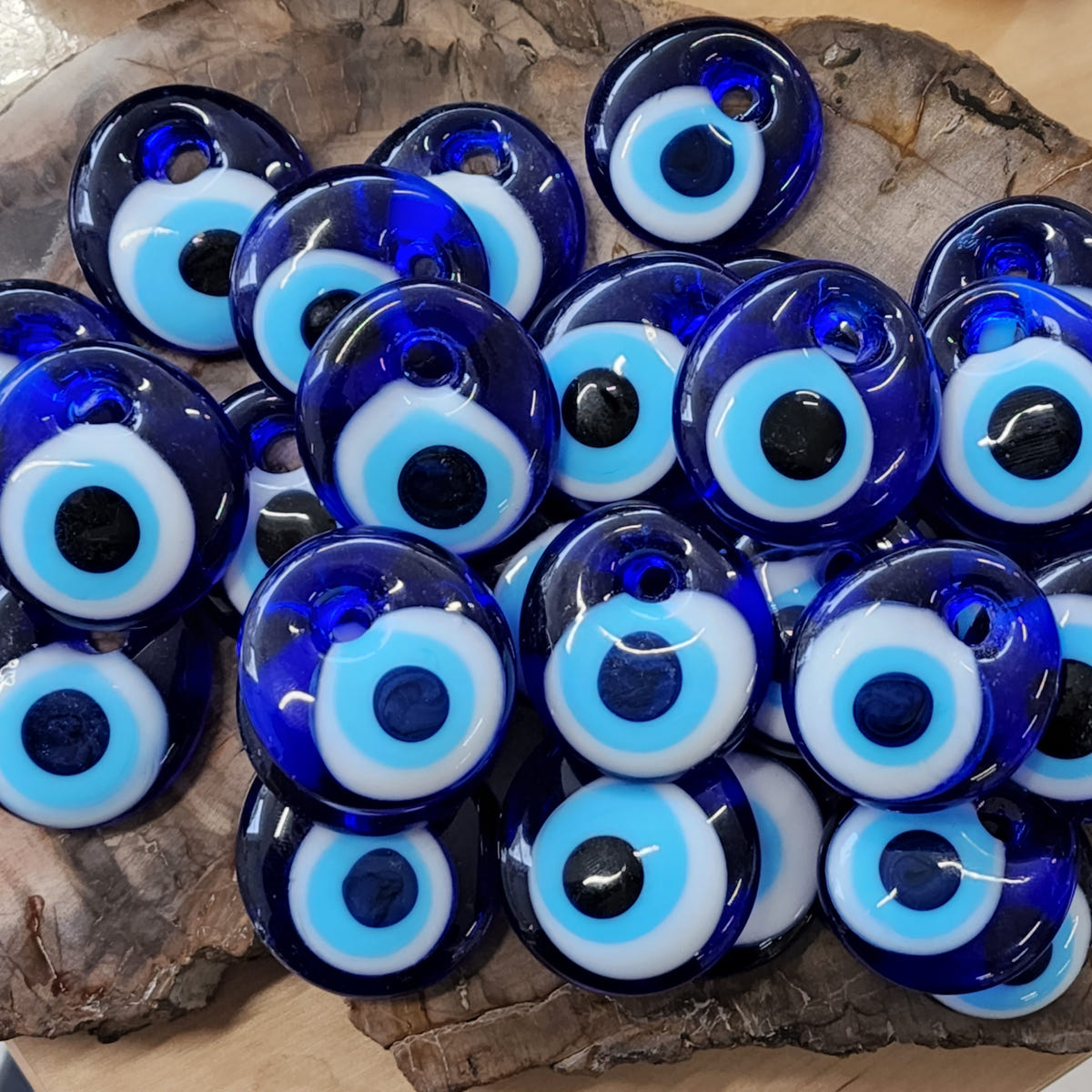 Small blue glass evil eye beads with white and turquoise rings arranged together in a bowl.